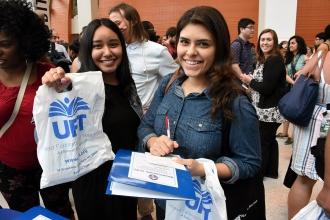 Two women smiling, holding up UFT bag