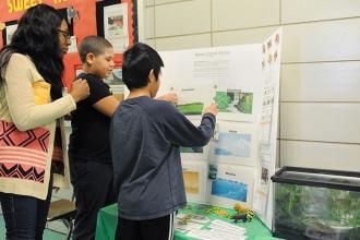 Paraprofessional Shermaine Alexander guides her students as they present their p