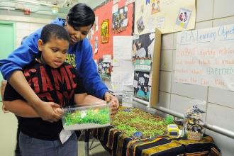 Kylah Hopkins helps a 3rd-grader present his grasslands habitat during the Galle