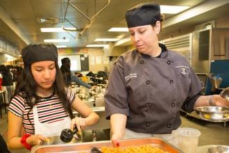 Culinary arts instructor Alexis DeVito works with a student in the kitchen.