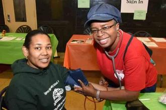 In the exhibit hall, nurse Chalesetta O’Neal checks the blood pressure of parent