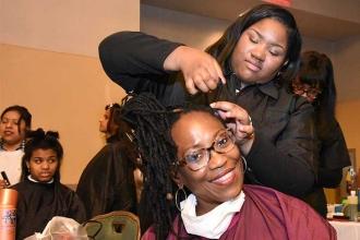 Parent Karen Chambers enjoys a new look that is being created for her by a cosme