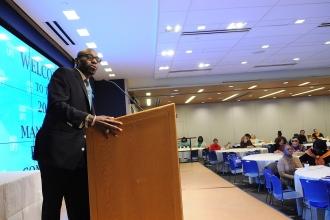 Man on stage behind a podium in front of an audience