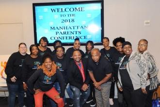 Group of people pose in a photo; smart screen behind them