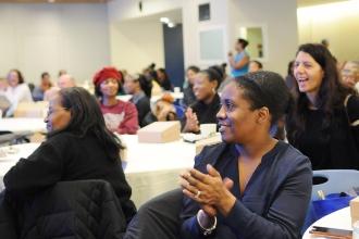 Women sitting at a table, one applauding