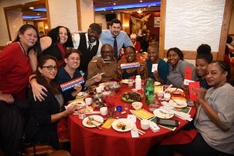 Group of people standing and seated at a table pose for photo