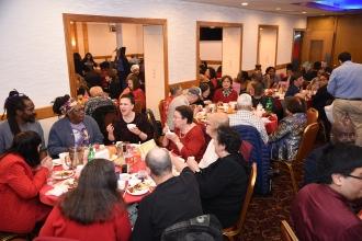 Group of people seated at a table dig into their food using chopsticks