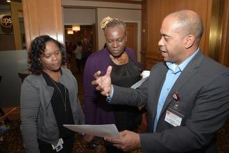 Three people looking at a paper and talking