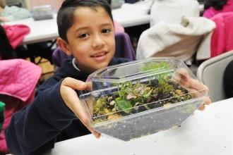 A student displays his completed terrarium.