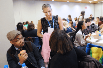 Standing woman speaks to seated man and woman