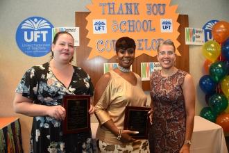 Three women holding plaques pose for camera
