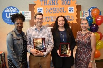 Three women and a man pose for a photo while holding plaques