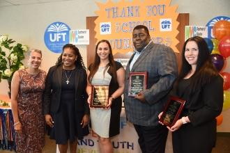 Four women and a man pose holding plaques
