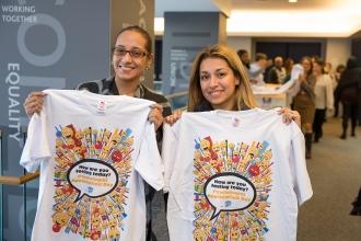 Two women holding up identical t-shirts.