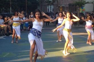 Student belly dancers perform for PS 19 families in the yard. 