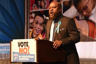 Sean Blanks leads the room in singing the national anthem.