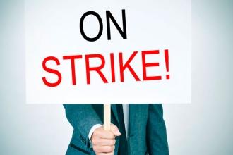 A man holding a sign that says "On Strike"