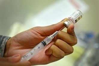 Hand holding a syringe pulling vaccination