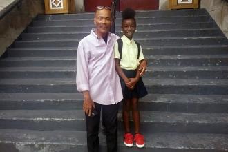 Man and girl wearing school uniform standing on school steps