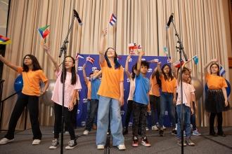 A group of students perform on stage while holding flags. 