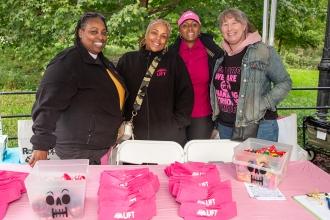 A group of four women pose in front of a fundraising table