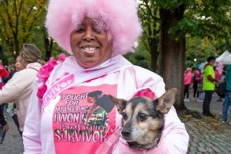 A woman poses for a photo with a pink wig and her dog in her arms