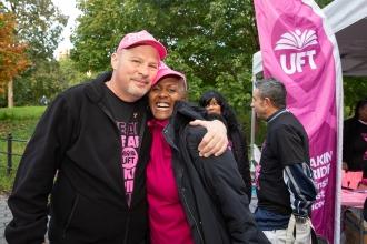 A man and a woman pose for a photo while wearing breast cancer awareness attire. 