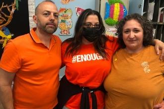 A group of staff members pose together wearing orange