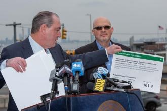 Two men stand at a podium during a press conference for a congestion pricing lawsuit
