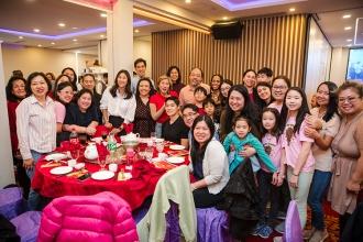 A large group of attendees from PS 42 in Manhattan gather around a table for a group photo at the 2024 UFT Lunar New Year celebration. 
