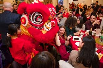 Students performing a Lion Dance at the 2024 UFT Lunar New Year celebration greet attendees at their tables.