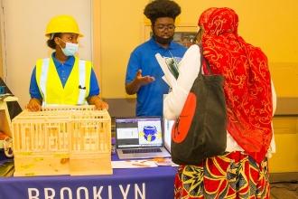 Two students show off a 3-d printer and model that it produced 