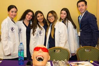 Students in lab coats with their teacher 