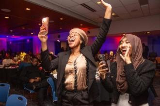 Two women celebrate as their colleague is announced as an award winner