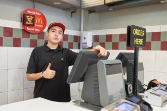 A fast food employee gives a thumbs up at the counter