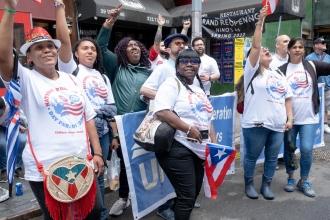 A group of members on the street raise their hands celebrating Puerto Rican pride.