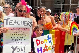 A woman and child hold up signs supporting LGBTQ+ 