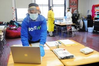 Student with facial shield and mask at computer