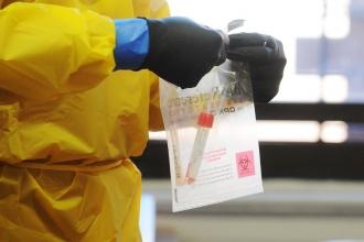 Person with protective clothing and vial