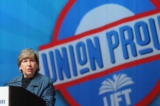 A woman speaks at a podium with a large "union proud" graphic in the background