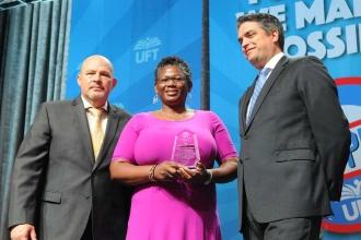 Two men pose for a photo with a woman who is holding an award. 