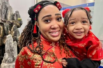 Faiza Khalid, a teacher and chapter leader at PS 36 in Manhattan, and her daughter dress in traditional Lunar New Year outfits and smile for a photo at the 2024 UFT Lunar New Year celebration. 