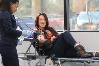 A woman smiles as she donates blood.