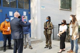 UFT President talks outside with school members. All are wearing masks, 