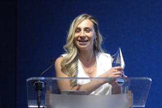 A woman smiles while showing off her award 