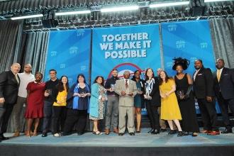 Two dozen award winners pose on stage for a photo