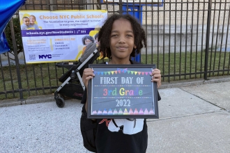 A student holds a "first day of third grade" sign