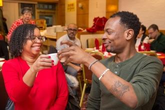 Two members, man and woman at a table, cheers to the Lunar New Year. 