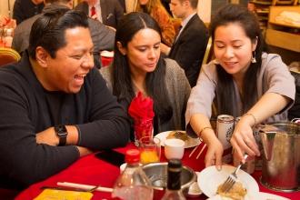 Three people at a table are sharing food... and a laugh. 