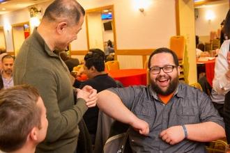 A man laughs while bumping elbows with a NY state Senator
